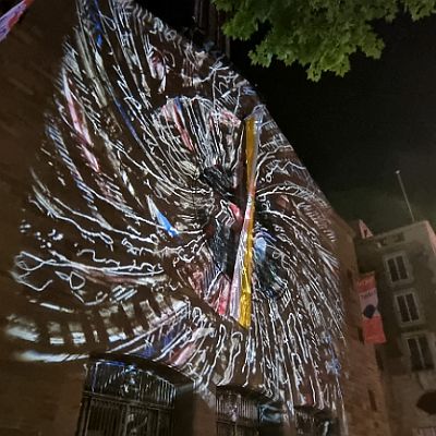 Eine Lichtinstallation auf der Fassade der Domkirche St. Eberhard Stuttgart  von den Künstlern Frederick D. Bunsen (Ammerbuch) und Philipp Contag-Lada (Stuttgart), 27. Mai 2022  Mit einem daguerreotypie-ähnlichen Verfahren, bei dem einzelne 18cm x 18cm große Glasplatten bearbeitet werden, wurden am 26. Mai mit einem großen Pani-Projektor (5000 kw) der Firma Musik Express in Stuttgart Bilder in ca. 40 Meter Entfernung auf die Fassade der Domkirche St. Eberhard projiziert, so dass die gesamte Kirchenfassade mit einer schwebenden Schrift im Sinne der Kunstform "Ecriture-Automatique" beleuchtet wurde. : St. Eberhard Stuttgart, Lichtinstallation, Bunsen, Contag-Lada, Kunst